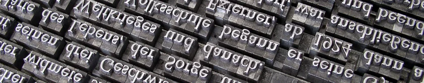 Rows of mirrored metal letterpress type blocks with German words such as "Lebens," "Volksschule" and "danach.