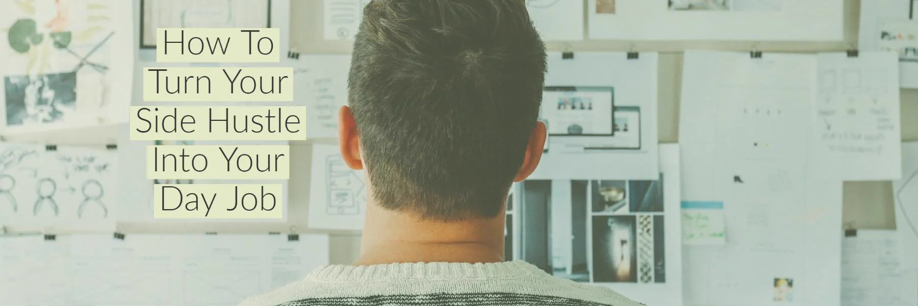 Man seen from behind facing a wall covered with pinned sketches, wireframes and photographs.