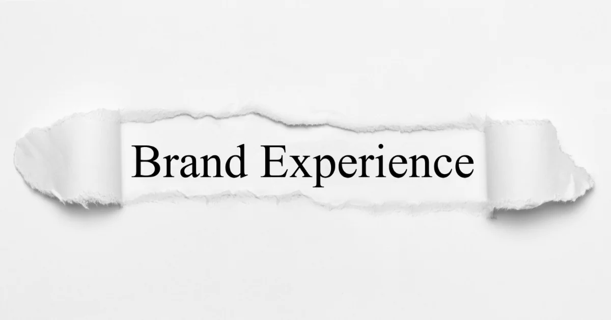 Torn white paper revealing the words "Brand Experience" in black serif type underneath.